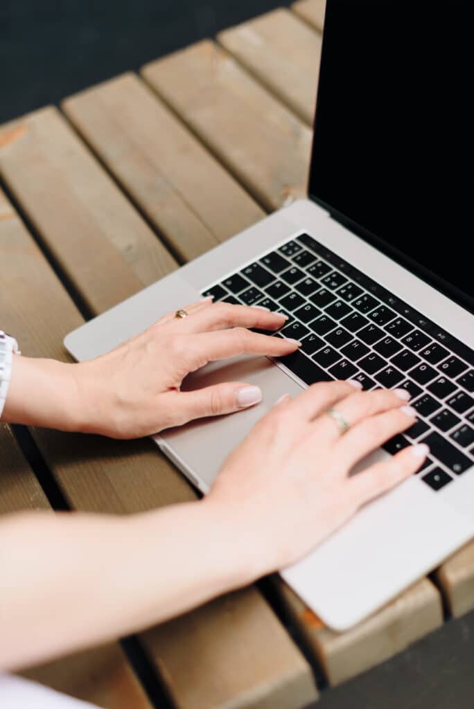 Hands of a woman with laptop in a summer outdoor cafe